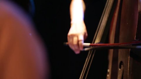 Man playing the contrabass, hand and bow detail close up. Classic music and tango from argentina. Old wooden contrabass.