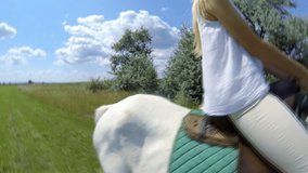 Young female sitting on the white horse outdoor under sky with clouds