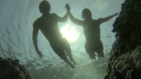 UNDERWATER: Couple swimming holding hands