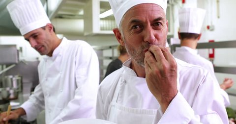 Portrait of smiling Caucasian chef showing his bolognese spaghetti in a commercial kitchen