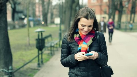 Young woman using smartphone during walk in city park
