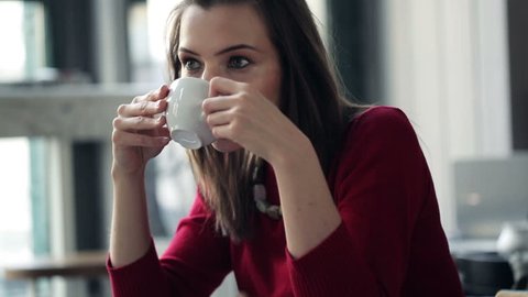 Pensive, thoughtful beautiful woman drinking coffee in cafe
