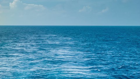 A Wake From a Ship at Sea with Blue Ocean Water, a Horizon, Blue Sky and Clouds. Video Stok