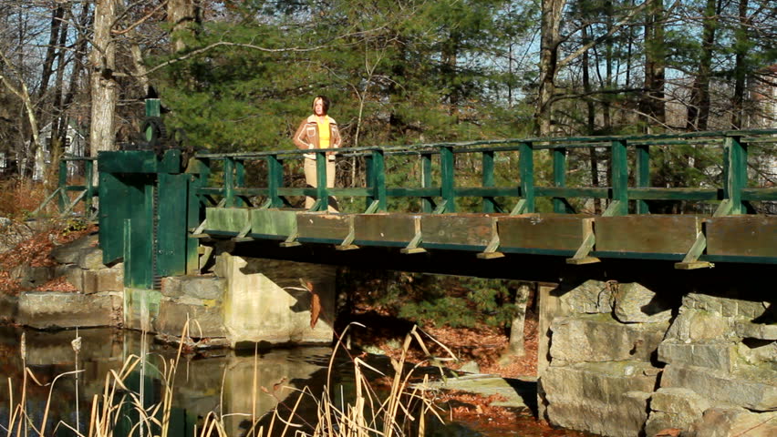 A woman walks over an old bridge.