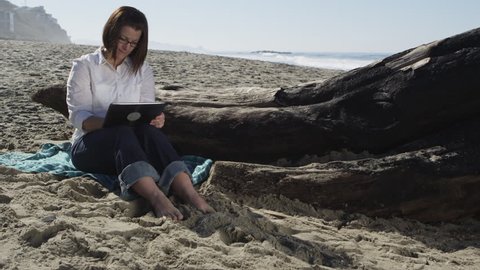Woman using digital tablet on the beach - 4K