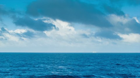 A Majestic Long Range Seascape with a Cruise Ship on the Horizon and Thunderous Clouds in a Blue Sky.