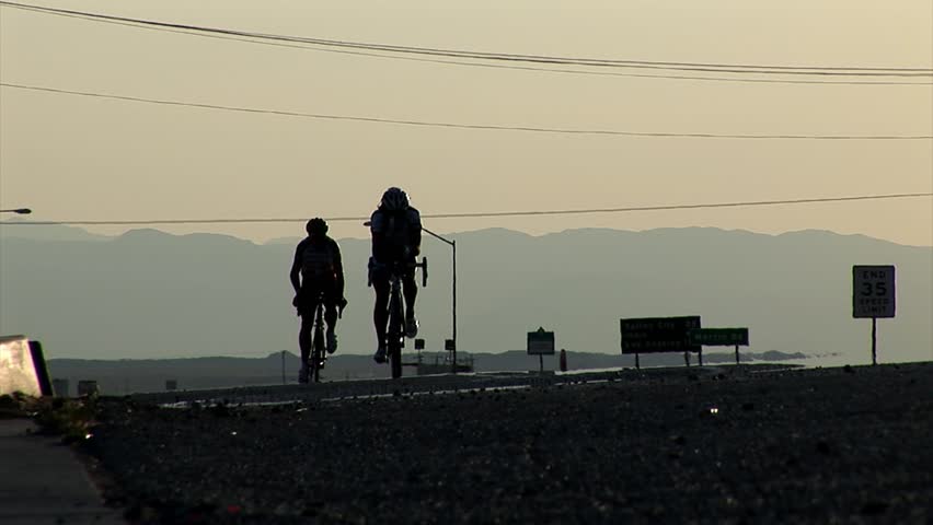 Two competing cyclists approach the camera at the dawn