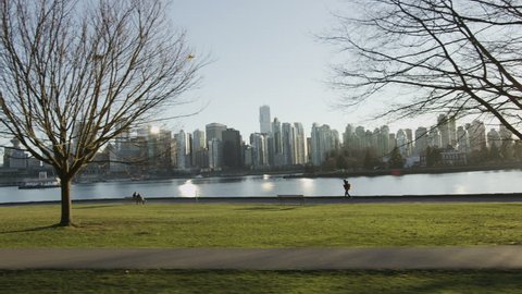 Dolly shot of Vancouver skyline with park and ocean.
