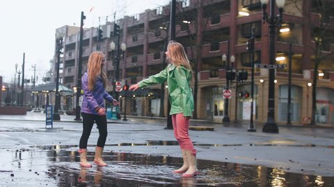 Two Friends Enjoy The Rain, Dance And Twirl In Big Puddle  스톡 비디오