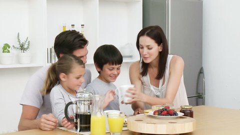 Happy young family having breakfast in the kitchen. Nutritive meal. Footage in high definition
