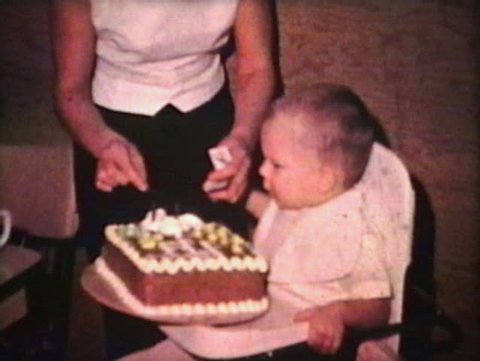 A cute little boy celebrates his second birthday and puts his hands on the side of the cake too! (Vintage 8mm film)