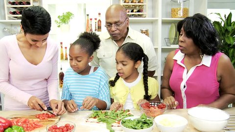 African American children home kitchen with mother grandparents learning make fresh homemade pizza slow motion - Three Generations Ethnic Family Kitchen Preparing Lunch