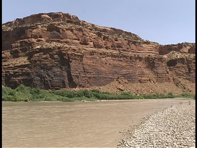 The muddy Colorado River winds its way through red sandstone canyons and formations near Moab, Utah.