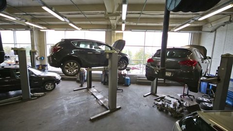 Cars on lifts and on floor at car workshop for repairing