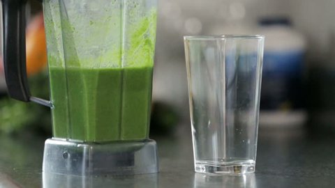Slow motion pouring a healthy, green smoothie made of blended fruits and vegetables. స్టాక్ వీడియో