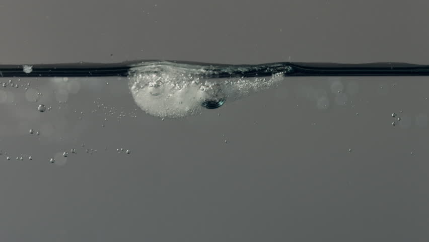 Ice cubes floating on water surface and rapidly melt.  Timelapse clip, recorded against gray background.