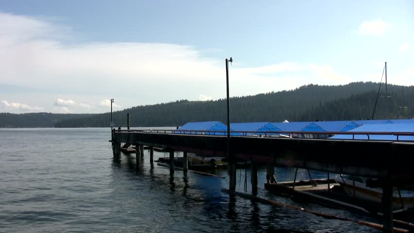 A pan from right to left, followed by a pan from left to right showing a dock, boats and a hotel, and a famous floating restaurant on Lake Coeur D