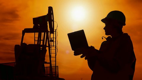 Silhouette worker and oil pump ; Silhouette worker-engineers which controls the oil pump with a laptop ,against the sunset,video clip
