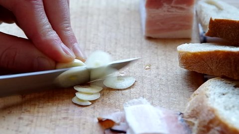 Slicing garlic with a knife on a wooden board
