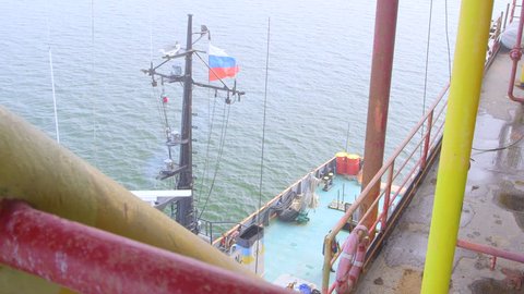 Offshore gas production platform in the East-Kazantip field, ship moored with Russian flag
