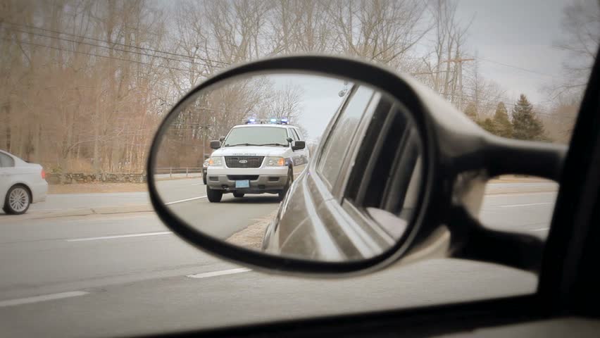 Police car in rear-view mirror highway traffic arrest  