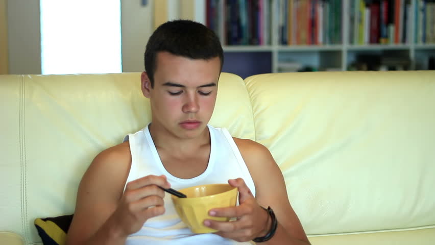 Teen eating cornflakes while watching and zapping television