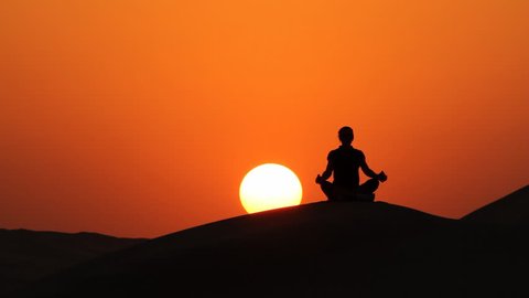 woman sitting in lotus position at amazing sunset