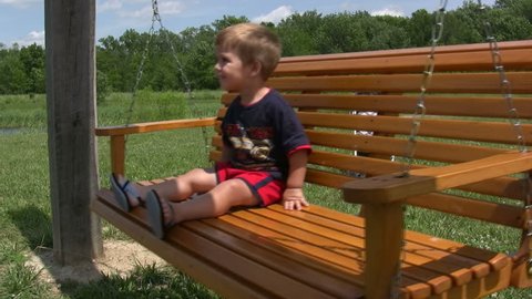 Young Boy Swinging on Hanging Bench