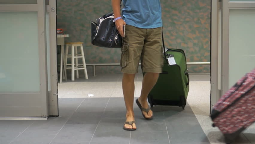 People arriving and walking through a busy airport with luggage and suitcases, from vacation or business trip. | Shutterstock HD Video #6018449