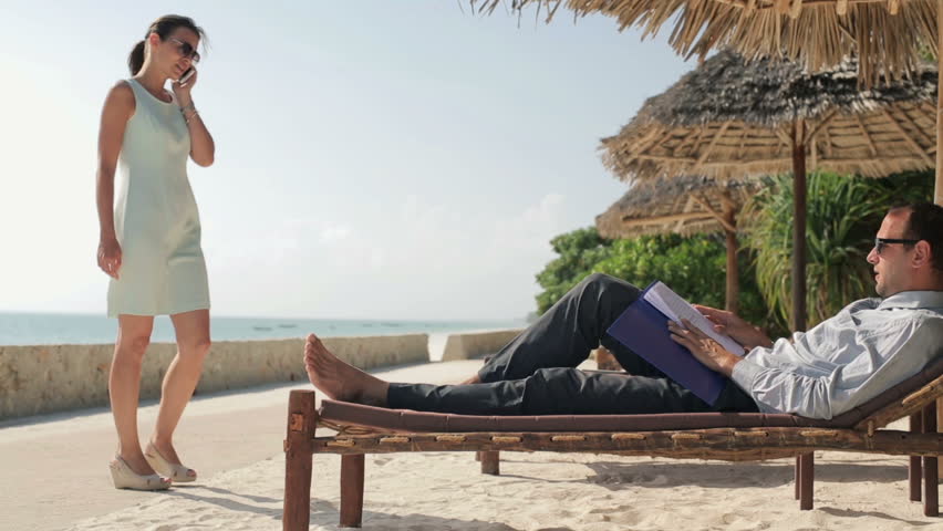 Business couple with cellphone and documents in exotic resort
