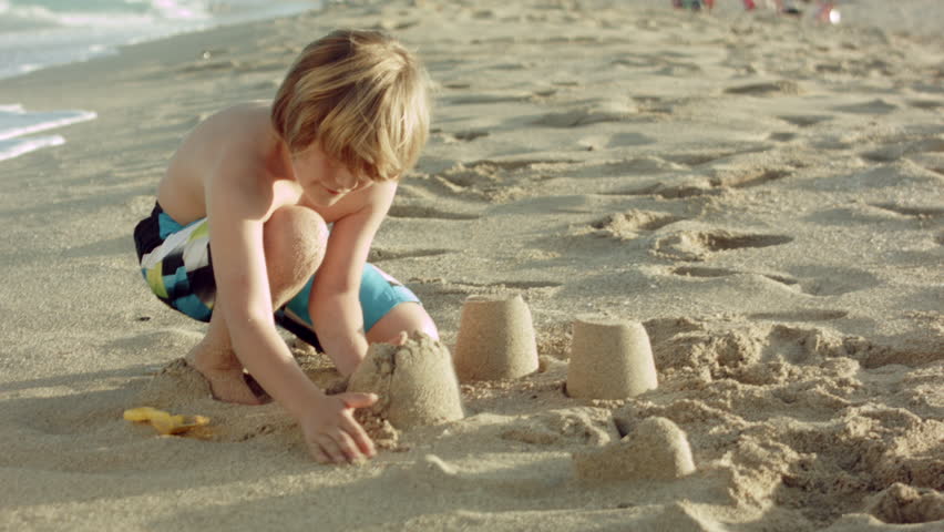 Little Boy Builds Sand Castle By Himself On The Beach