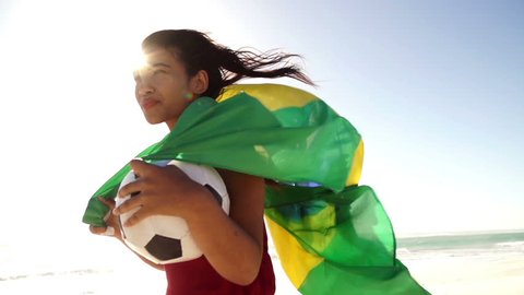 Brazilian soccer fan with ball and waving flag in slow motion