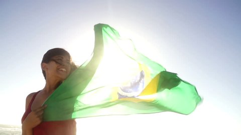 Woman waving brazilian flag at the beach in slow motion