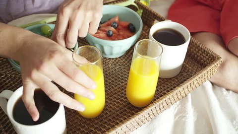Close up shot of a man and woman picking up juice off of a tray on a bed