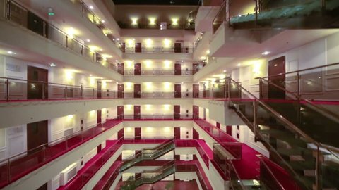 View from downward movement elevator to floors with balconies and many doors in hotel