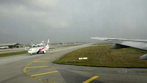 Kuala Lumpur, Malaysia: March 2013 -airplane driving to starting area in Kuala Lumpur and waits for take off. Some other airplanes waiting in a line. Dark clouds visible, some stripes from the window.