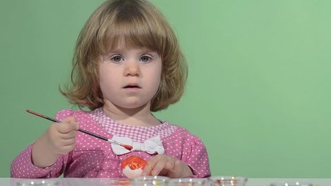 Little girl painting easter eggs