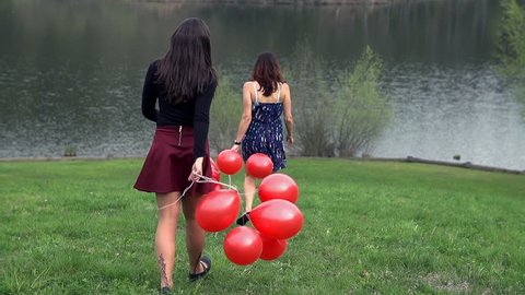 Girls With Red Balloons Walking Down The Slope