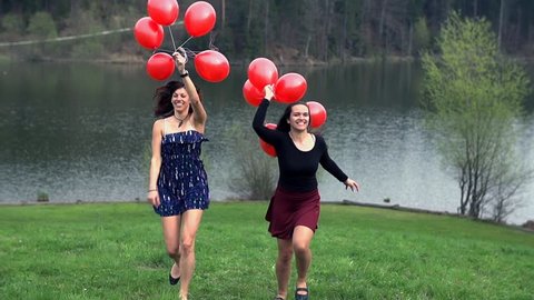 Two Girls Running Towards The Camera With Red Balloons in Slow Motion