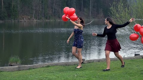 Two Young Ladies Enjoying Life At Lake With Red Balloons In Slow Motion
