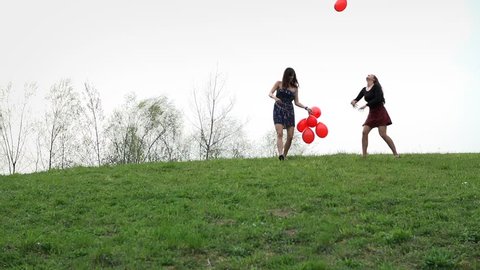 Girls In Charming Dresses Throwing Balloons In Air On Hill