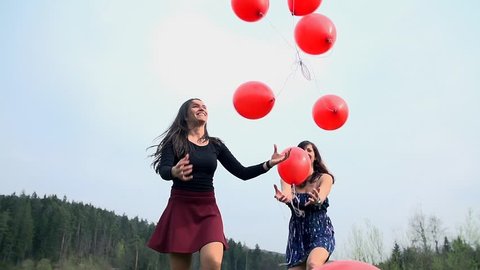 Female Friends Throwing Balloons In To Air Having Fun