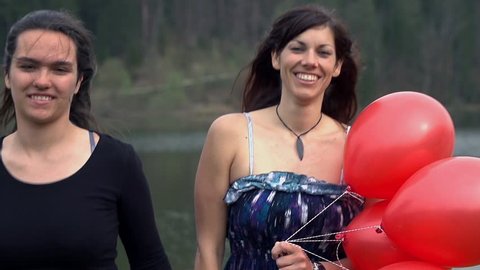 Female Friends In Elegant Dress Running With Red Balloons