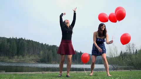 Two Women Enjoying Life At Lake Throwing Balloons In Air