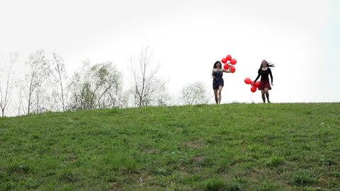 Two Attractive Woman Running Down The Hill With Red Balloons