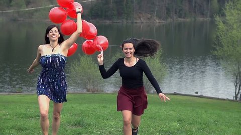 Two Girls Enjoying Life Running With Red Balloons In Dresses
