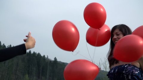 Close Up On Girl In Dress Playing With Red Balloons In Nature
