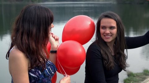 Two Female Friends In Beautiful Dress And With Red Balloons