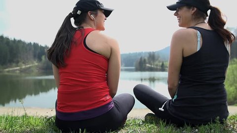Two Fit Female Friends Resting Beside The Lake