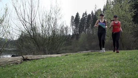 Slow Motion Tracking Two Girls Running Beside Lake